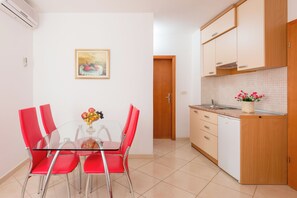 Eine moderne Küche mit einem Glastisch, roten Stühlen, einem Holzschrank und einer gefliesten Spritzschutzwand.