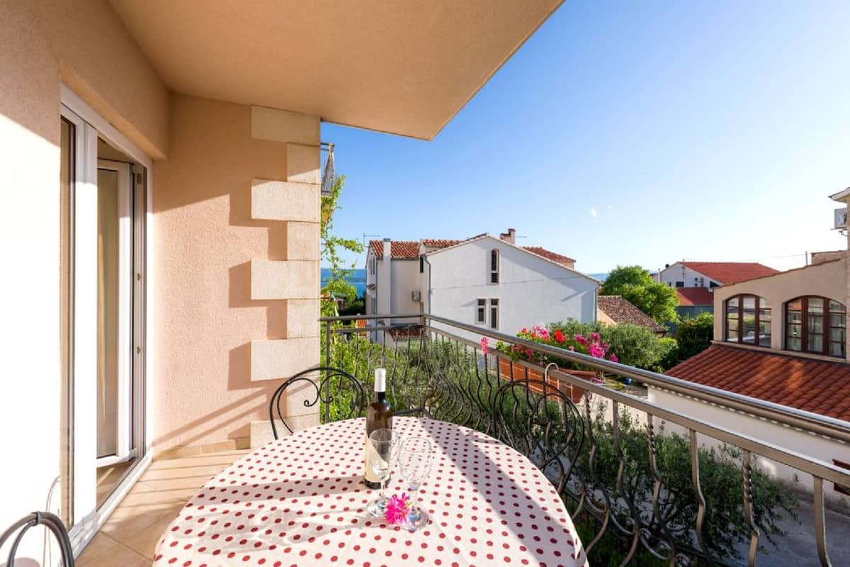 A balcony with a table, a bottle, and a glass.