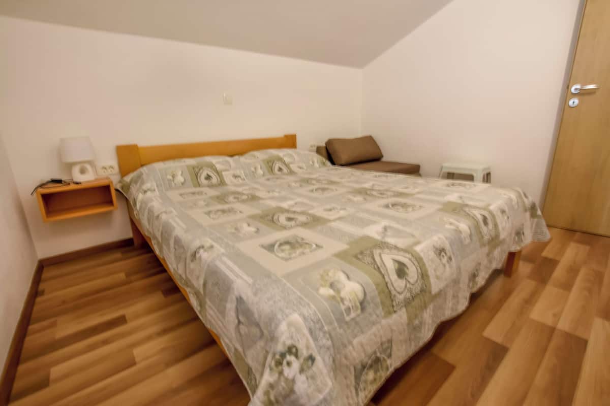 Une chambre à coucher avec un lit en bois, une table de chevet avec une lampe et un petit tabouret.