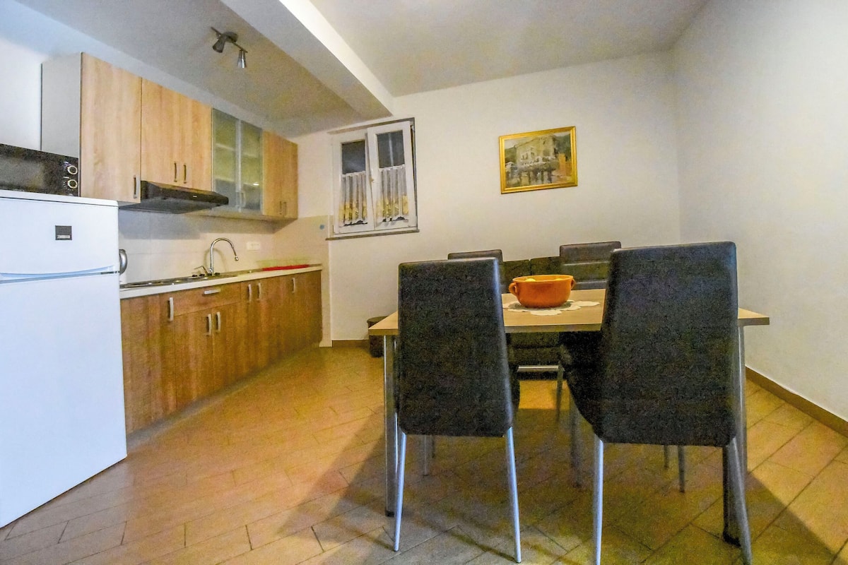 Une cuisine compacte avec des meubles en bois, un réfrigérateur blanc et un coin repas comprenant deux chaises et une table.