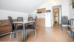 Et kompakt køkken med spiseplads, en sofa og et lille bord med stole.