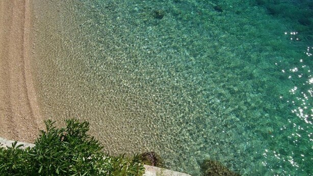Ein Strand mit klarem, flachen Wasser und sandigem Ufer.