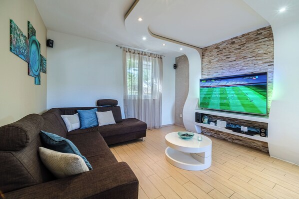 Un salon moderne avec un grand téléviseur à écran plat, un canapé marron et une table basse blanche.