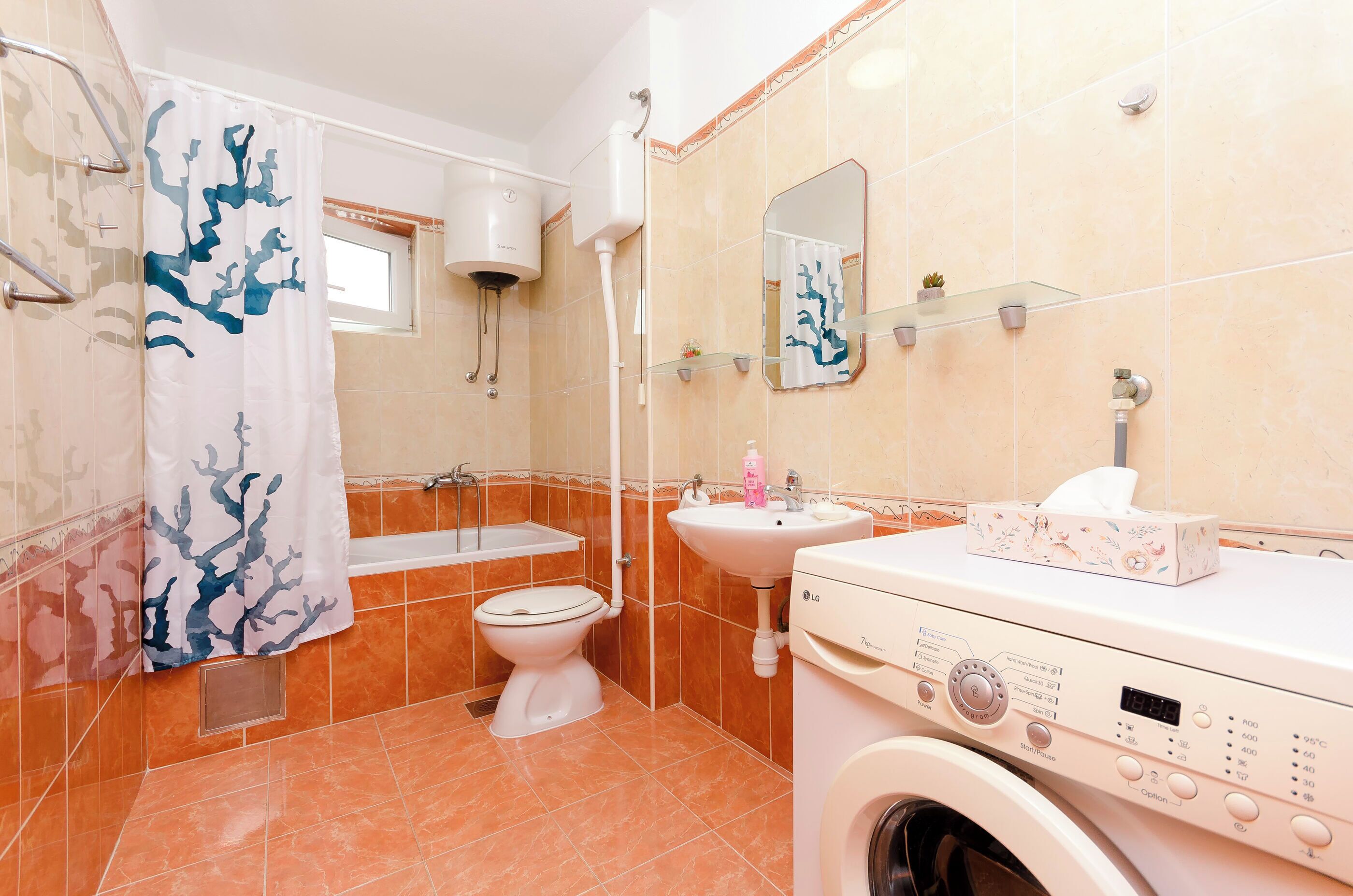 Un baño con lavadora, inodoro, lavamanos y cortina de ducha.