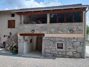 A two-story stone building with a balcony, a small porch, and a door leading to an interior space. - Apartment Balidur (Buzet)