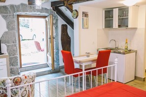 A cozy kitchen with a dining area, stone walls, and a view of the outdoors. - Apartment Balidur (Buzet)