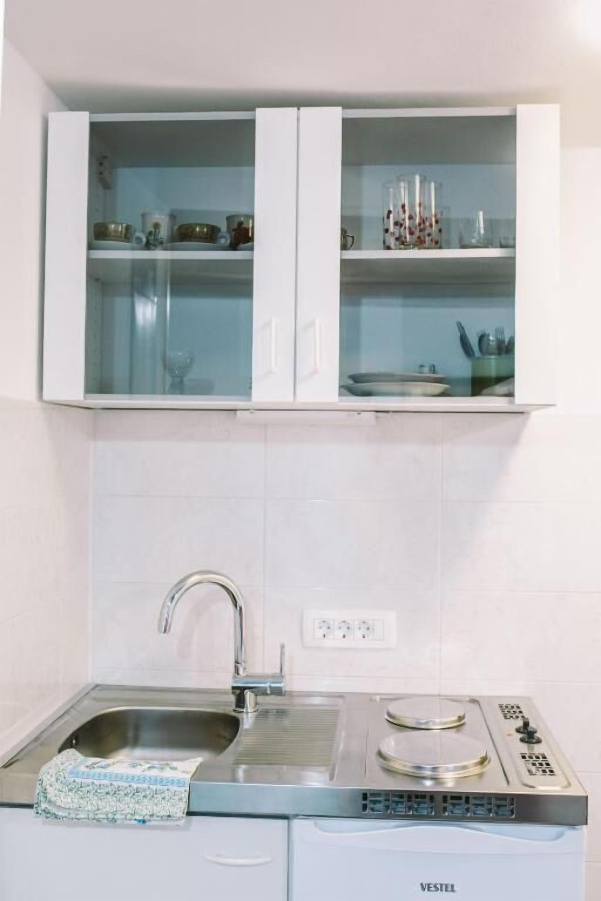 A kitchen with white cabinets, a stainless steel sink, and a built-in stove.