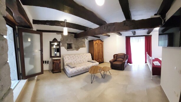 Ein geräumiges Wohnzimmer mit freiliegenden Holzbalken, einer Couch, einem Sessel und einem kleinen Tisch.