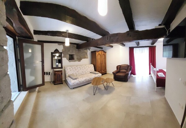 A spacious living room with exposed wooden beams, a sofa, a chair, and a small table. - Apartment Balidur (Buzet)