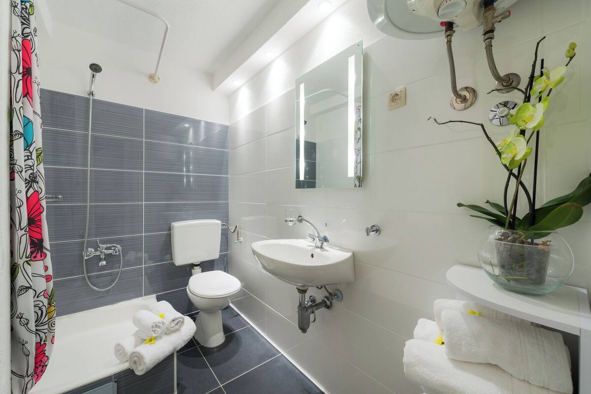 Un bagno moderno con doccia, wc, lavandino e specchio.