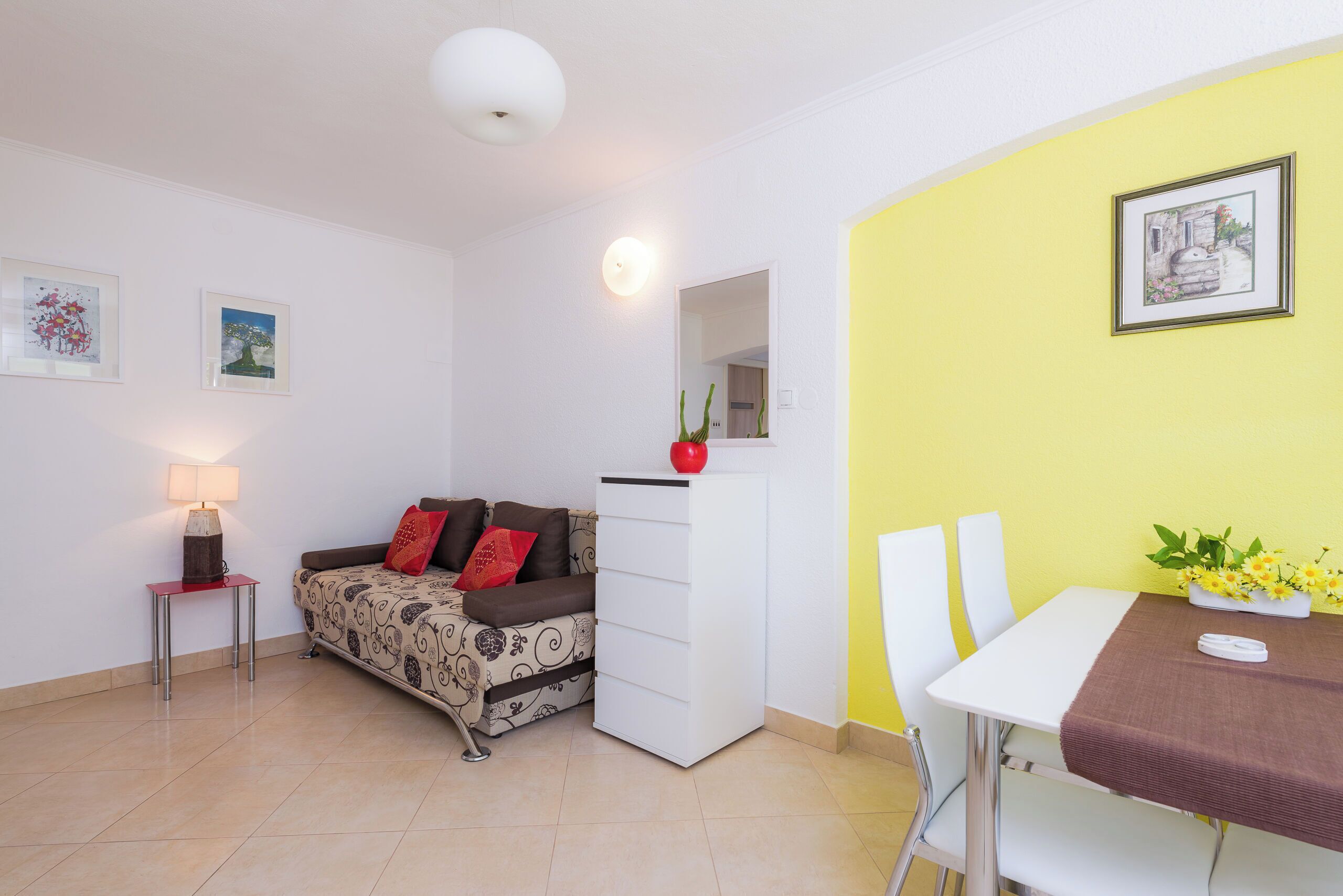 A compact living space with a bed, a small table, a dining table, and a sofa.
