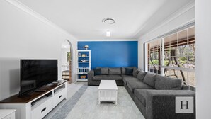 Ein modernes Wohnzimmer mit einer Eckcouch, einem Flachbildfernseher, einem weißen Couchtisch und einer blauen Akzentwand.