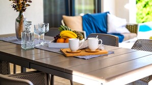 A dining table set with a fruit bowl, two white mugs, and a glass vase with dried flowers. - Villa Royal Green Three (Policnik)