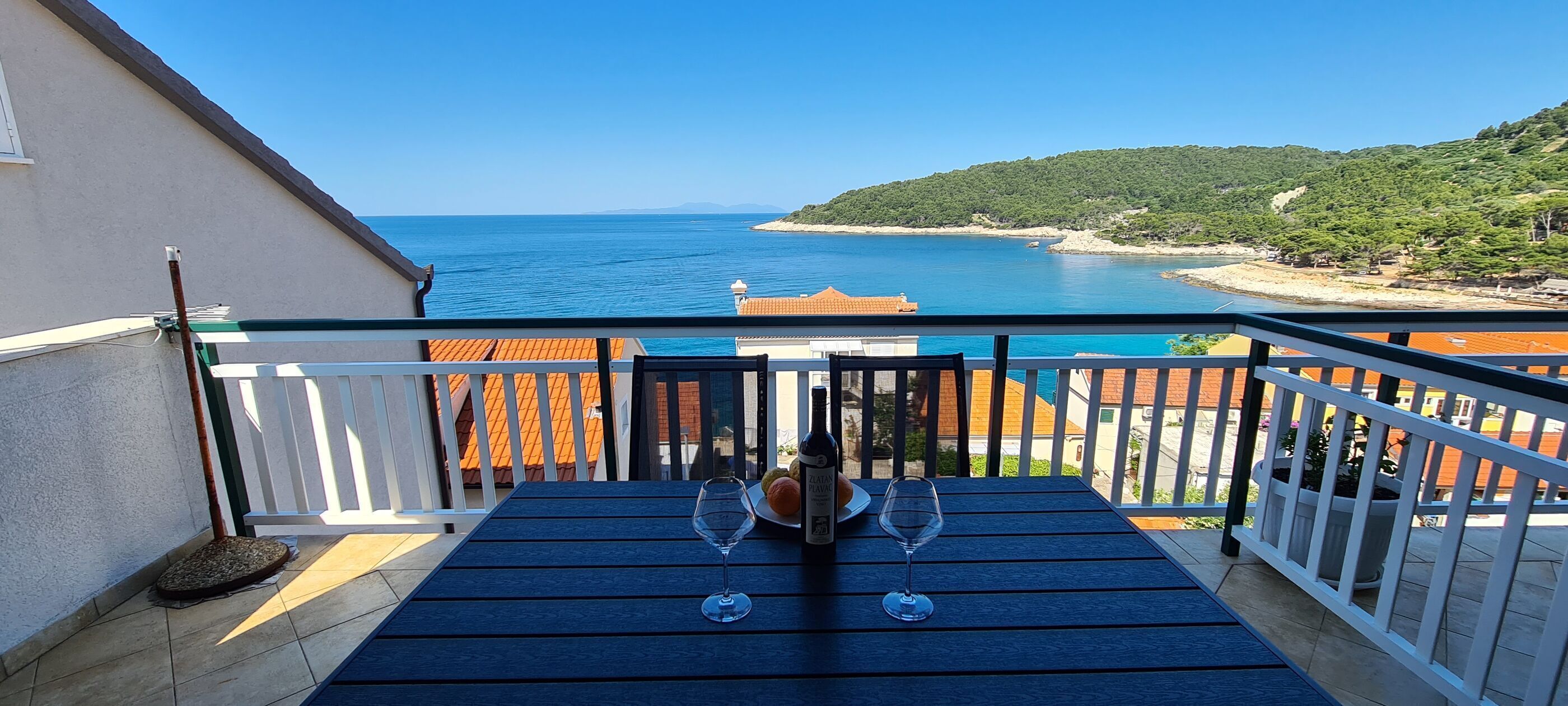 A balcony with a view of the sea and a hillside.