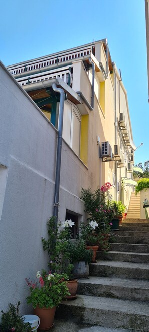 A building with a staircase leading up to a door, surrounded by potted plants and flowers. - Apartment Moli Onte Holiday (Hvar)