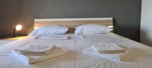 A neatly made bed with white linens and folded towels, a bedside lamp, and a wooden headboard. - Apartment Moli Onte Holiday (Hvar)
