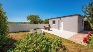 A modern house with a patio, outdoor seating, and a view of the sea. - House Peroj (Vodnjan)