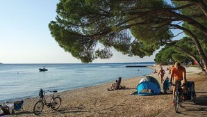 A beach with a tent, a bicycle, and a boat in the water. - House Peroj (Vodnjan)