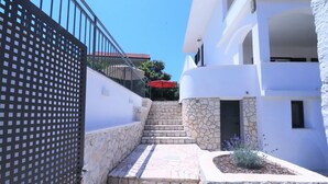 A narrow stone staircase leading to a white building with a stone wall on one side and a metal fence on the other. - House Villa Mendula (Okrug)