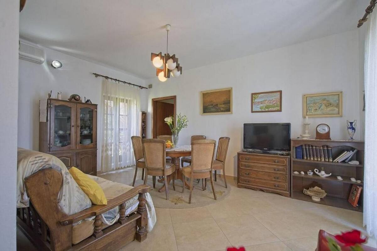 A living room with a dining table, chairs, a TV, and a bookshelf.