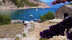 A coastal scene with boats on a clear blue sea, rocky terrain, and a stone building. - House Peacefull Relax (Jelsa)