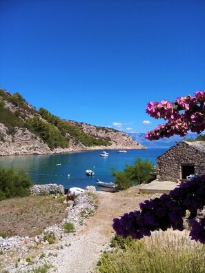A coastal scene with boats on a clear blue sea, rocky terrain, and a stone building. - House Peacefull Relax (Jelsa)