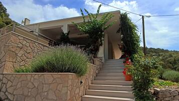Una scala conduce a un edificio moderno con pareti in pietra e presenza di vegetazione.