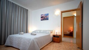 A neatly made bed with pillows and a rolled towel, a bedside table with a lamp, and a door leading to another room. - House Peacefull Relax (Jelsa)