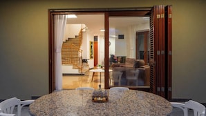 A dining area with a round table, white chairs, and a glass partition. - Villa Rita (Sveti Filip i Jakov)