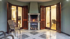 A corner room with a fireplace, wooden shutters, and a seating area with chairs. - Villa Rita (Sveti Filip i Jakov)