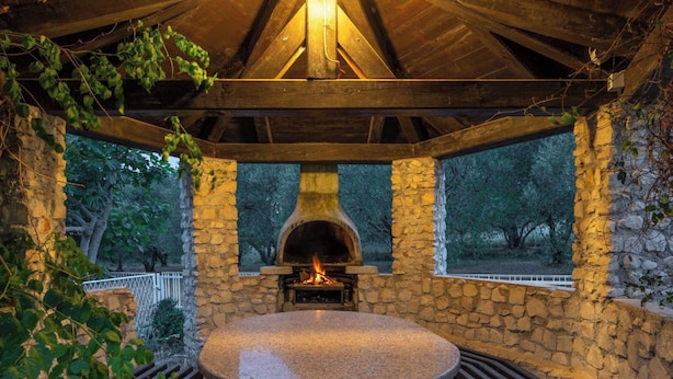 A stone-built outdoor pizza oven under a wooden roof, surrounded by stone walls and a stone bench. - Villa Rita (Sveti Filip i Jakov)