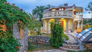 A two-story house with a curved balcony, stone walls, and a stone pathway leading to the entrance. - Villa Rita (Sveti Filip i Jakov)