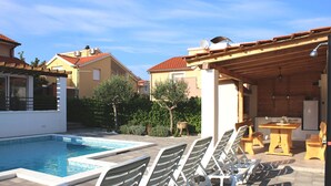 A swimming pool with lounge chairs and a wooden pergola. - Villa Divine (Vodice)