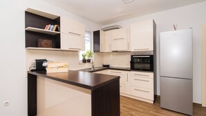 A modern kitchen with a central island, built-in cabinets, a stainless steel refrigerator, and a microwave. - Villa Divine (Vodice)