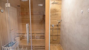 Un'area doccia moderna con pareti divisorie in vetro, rivestimenti in legno e soffione.