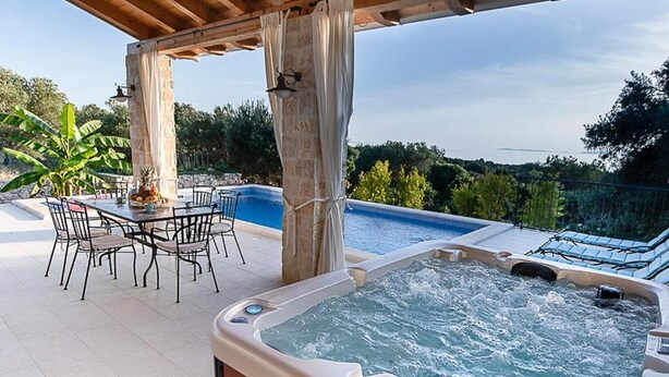 Una vasca idromassaggio, piscina esterna e area pranzo con sedie e tavolo.