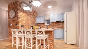 Una cucina con parete in mattoni, una sveglia, un frigorifero e un'area bar con sedie.