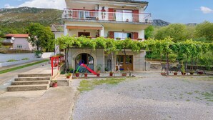 A two-story building with a balcony, a red slide, and potted plants. - Apartment Ivona (Vinodol)