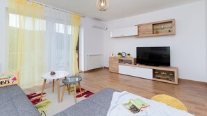 A modern living room with a sofa, a small round table, a TV, and a wooden cabinet. - Apartment Ivona (Vinodol)