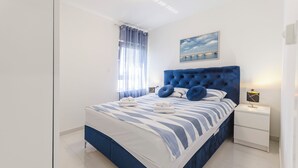 Ein modernes Schlafzimmer mit einem großen Bett, einem Nachttisch, einer Wandlampe und einem Fenster mit Vorhängen.