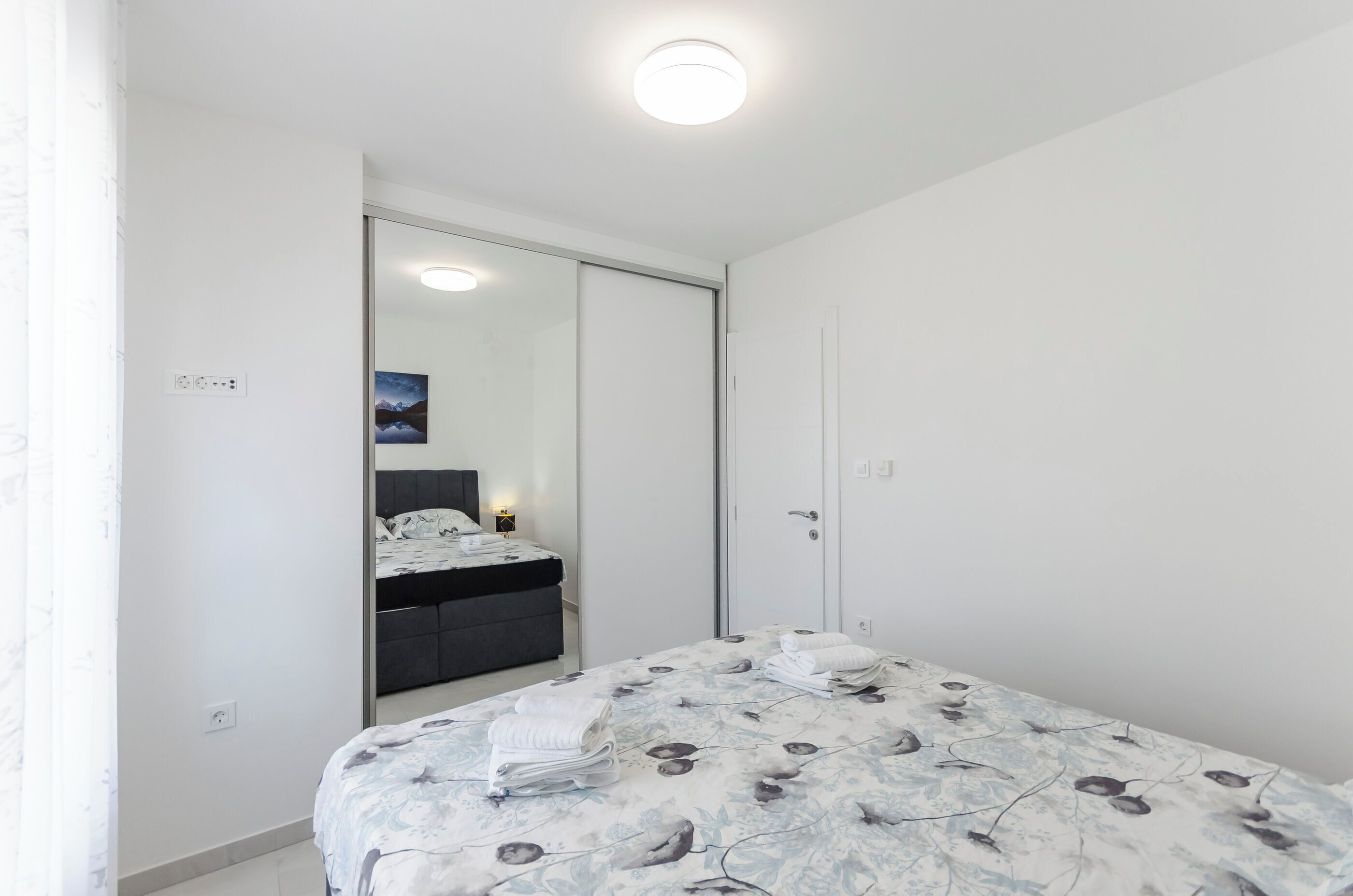 Un dormitorio con cama, armario, mesita de noche y espejo.