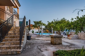 Una zona residenziale con una scala in pietra che conduce a un balcone, una piscina e un SUV parcheggiato.