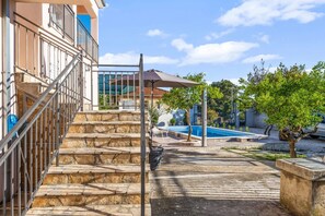 Una scala in pietra conduce a un edificio, una piscina e un albero.