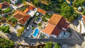 An aerial view of a residential area with houses, a swimming pool, and a road.
