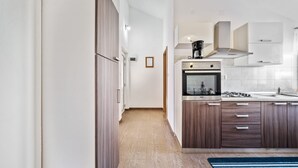 A modern kitchen with a built-in oven, stainless steel appliances, and wooden cabinets.