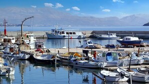 A marina with various boats docked, a lighthouse in the background, and mountains in the distance. - Apartment Iskra (Split)