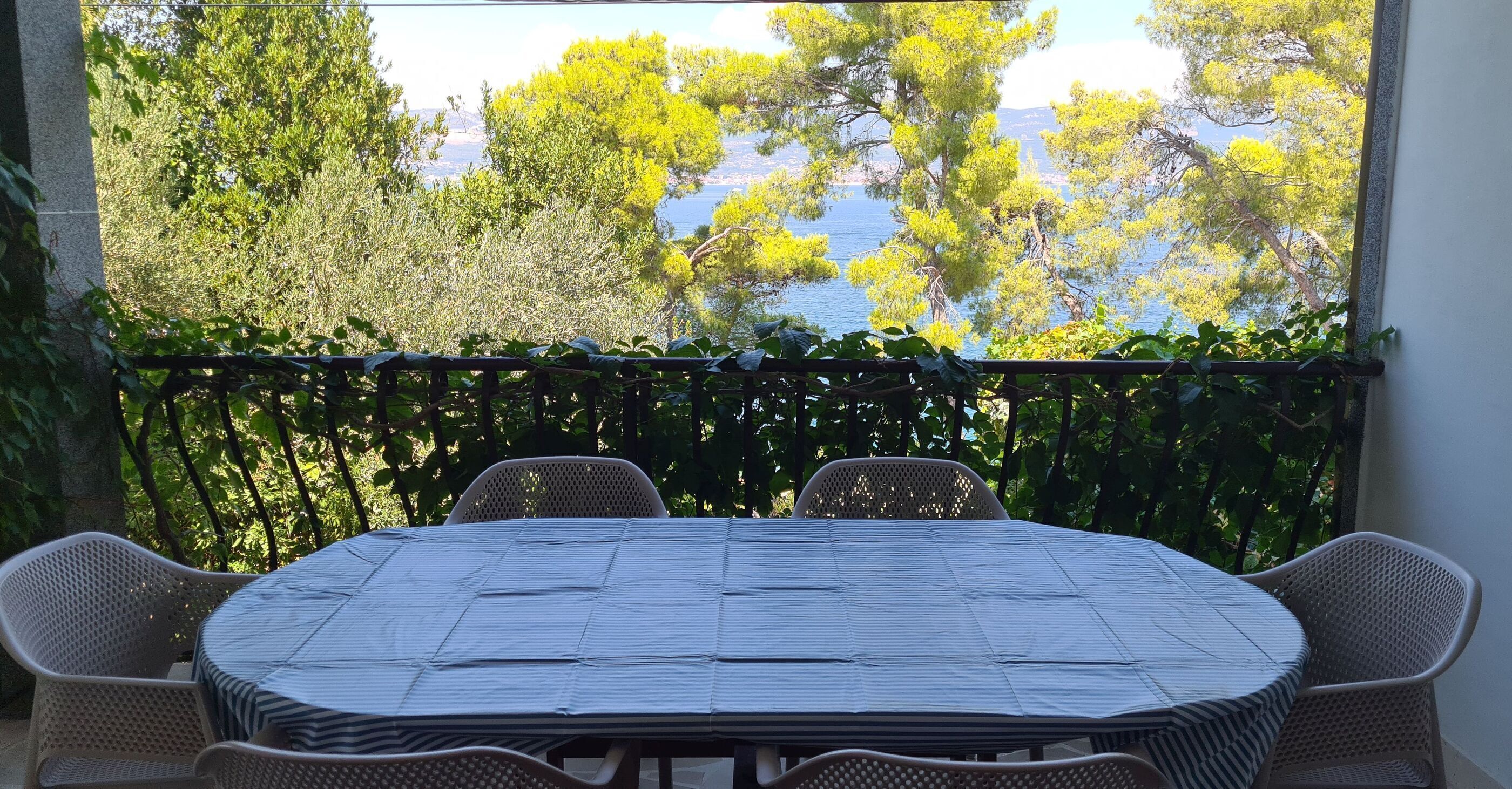 A balcony with a table and chairs, overlooking a body of water and trees.