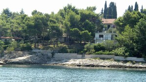A coastal property with a stone wall, a small building, and dense trees. - Apartment Iskra (Split)