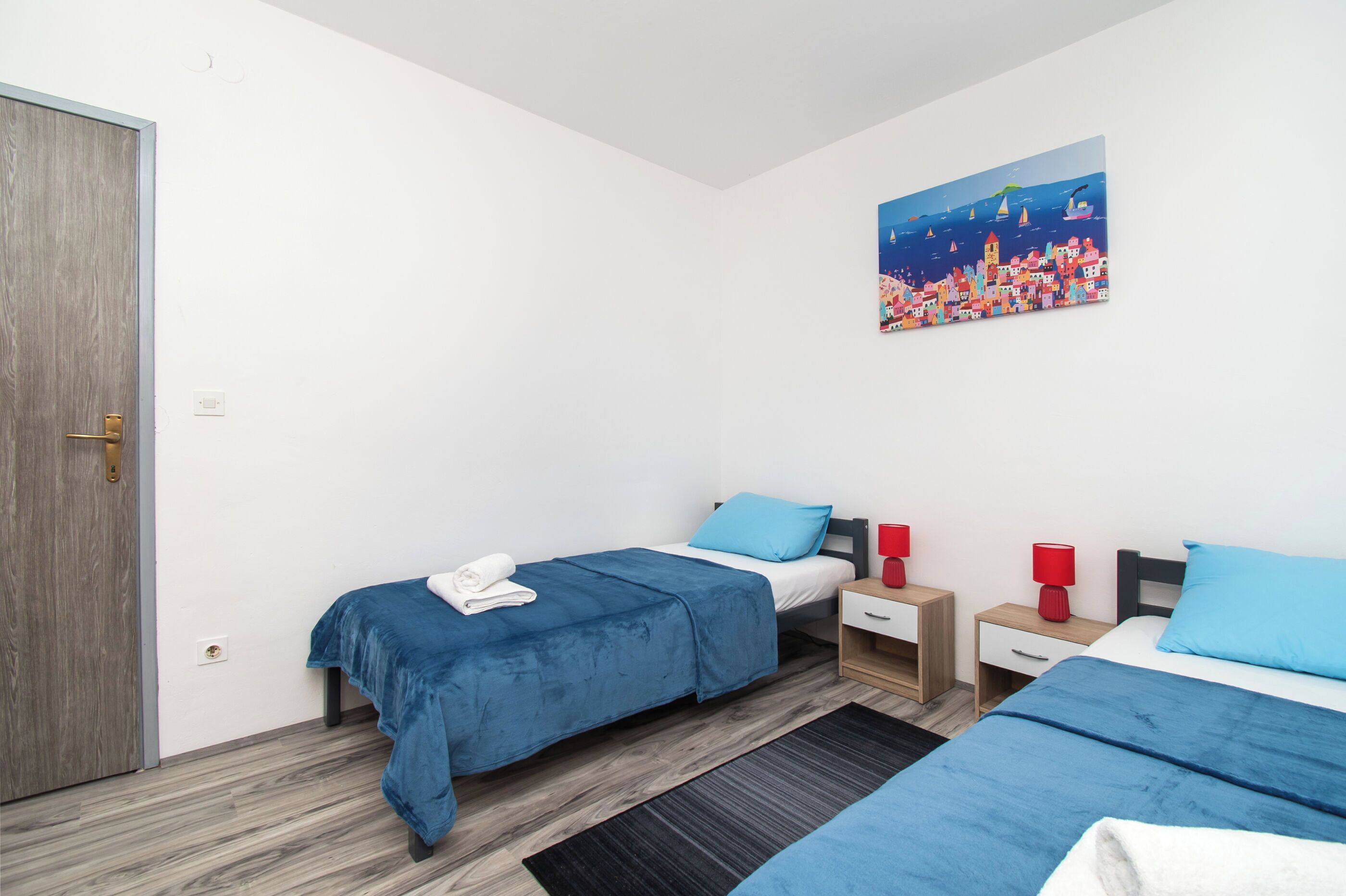 Une chambre d’hôtel avec deux lits, un tableau au mur et une porte en bois.