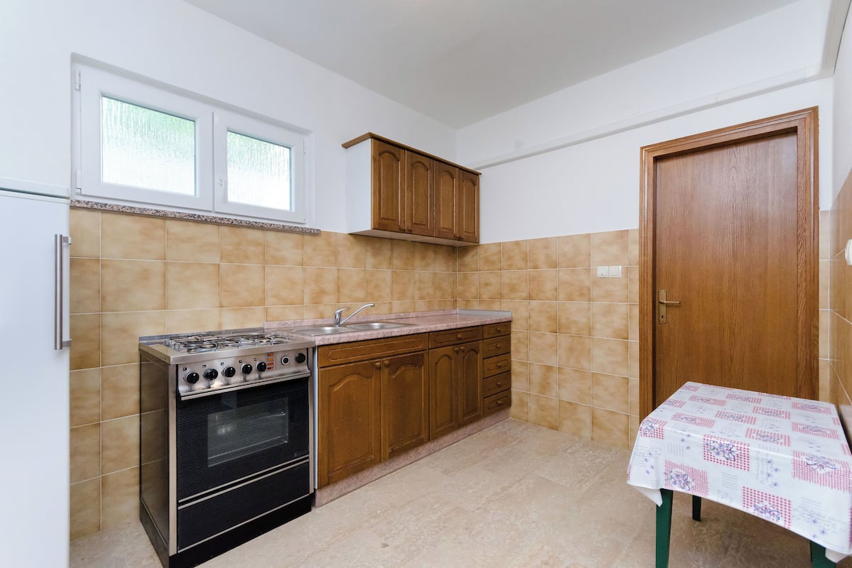 Uma cozinha com fogão, pia, armários de madeira e painel de azulejos.